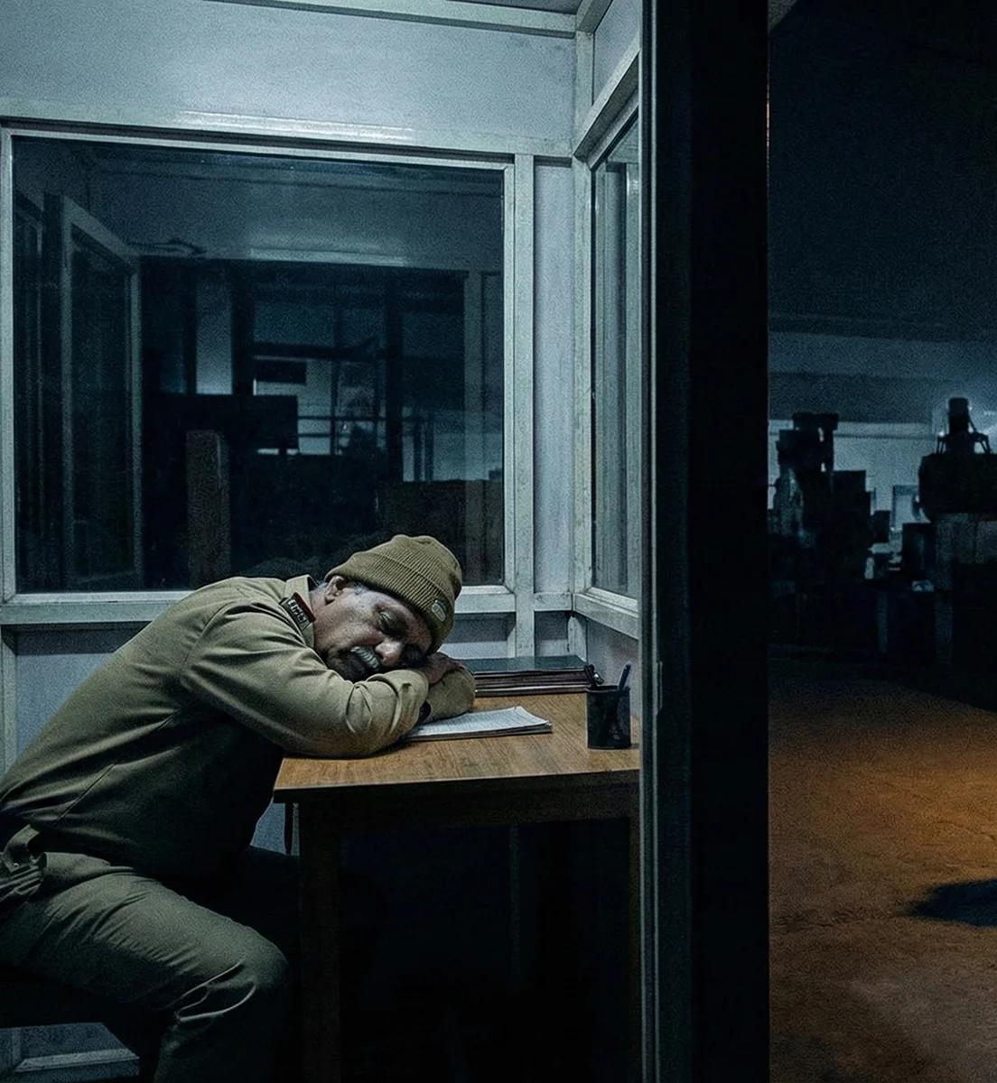 Blind spots or poor footage hide evidence: Security guard sitting inside a booth reading, illustrating missed activity and blind spots due to poor vigilance or weak camera coverage